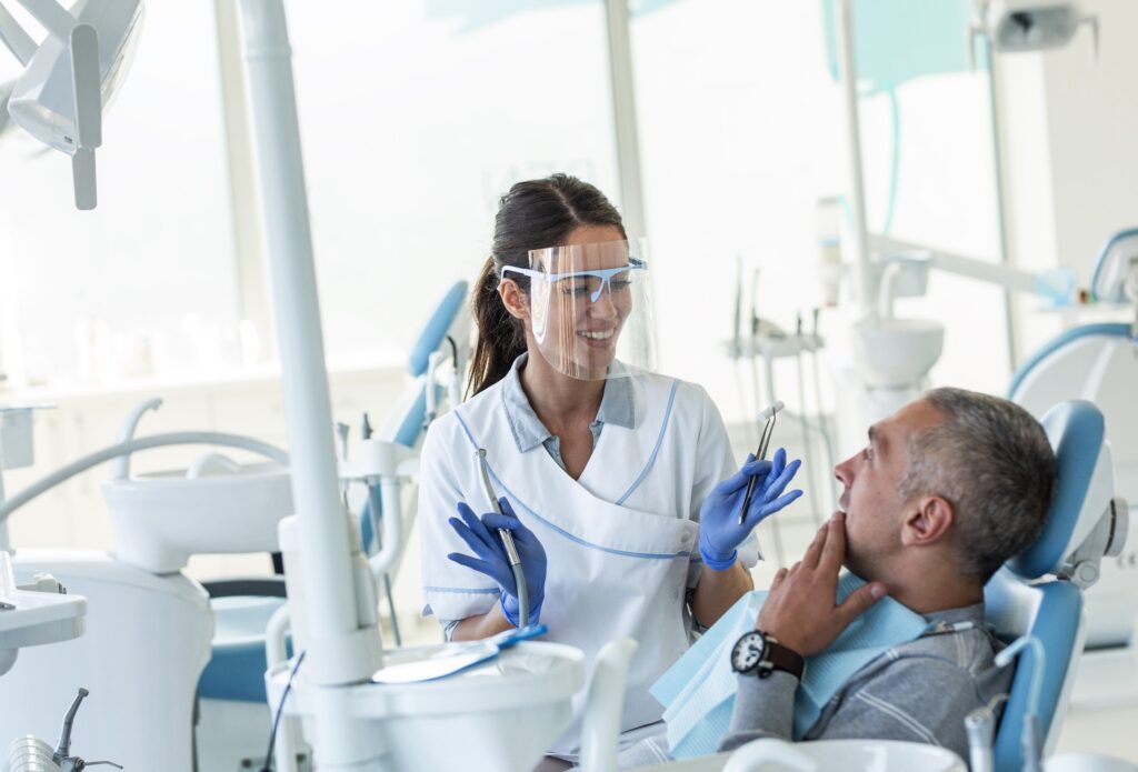 Smiling dentist talking to patient in treatment chair